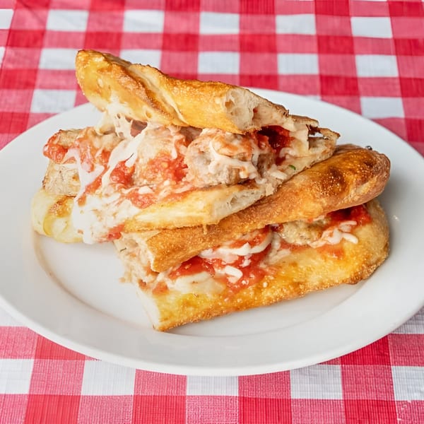 Doughboys Pizzeria's meatball sub, sliced and served on a white plate with a red and white checkered tablecloth.