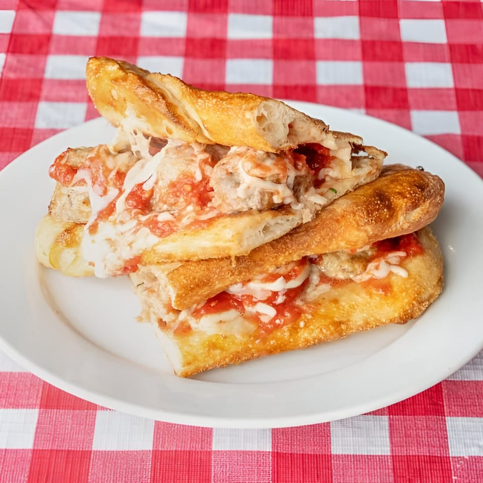 Doughboys Pizzeria's meatball sub, sliced and served on a white plate with a red and white checkered tablecloth.