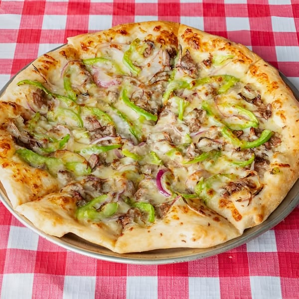 Doughboys Pizzeria's Italian sausage pizza with green peppers and red onions on a red and white checkered tablecloth.
