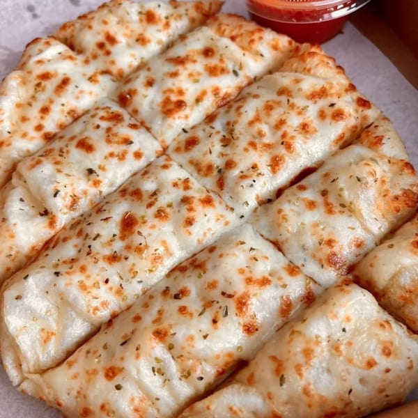 Cheesy garlic breadsticks from Doughboys Pizzeria, with a side of marinara sauce.