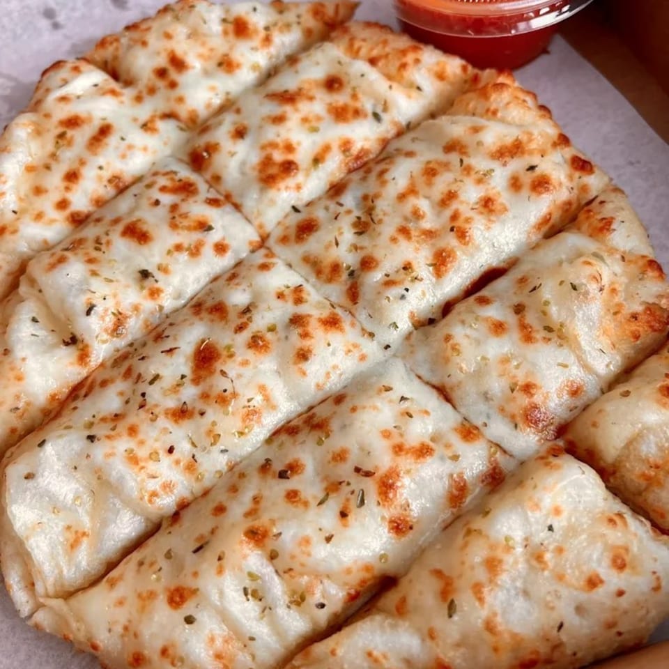 Cheesy garlic breadsticks from Doughboys Pizzeria, with a side of marinara sauce.